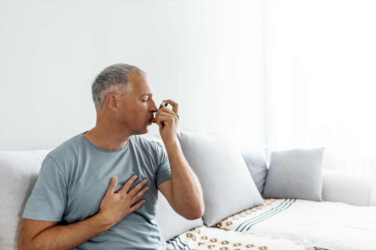 Un bărbat matur tratează astmul cu un inhalator acasă