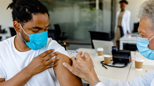 A young man receiving a COVID-19 vaccine or booster from a healthcare worker