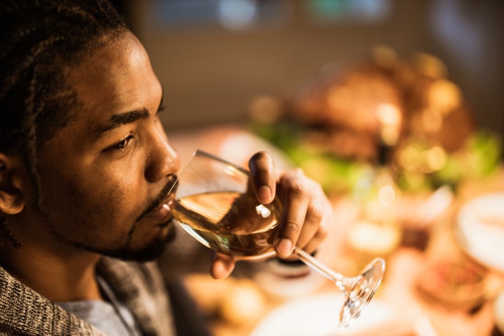 man enjoying while drinking wine at home and looking away.