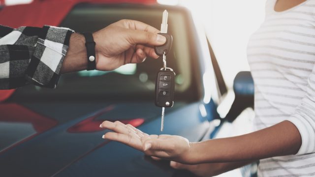 Man giving a woman car keys at a dealership