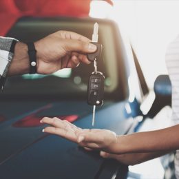 Man giving a woman car keys at a dealership