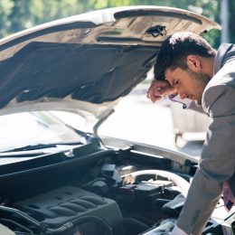 Man looking down at the hood of his car