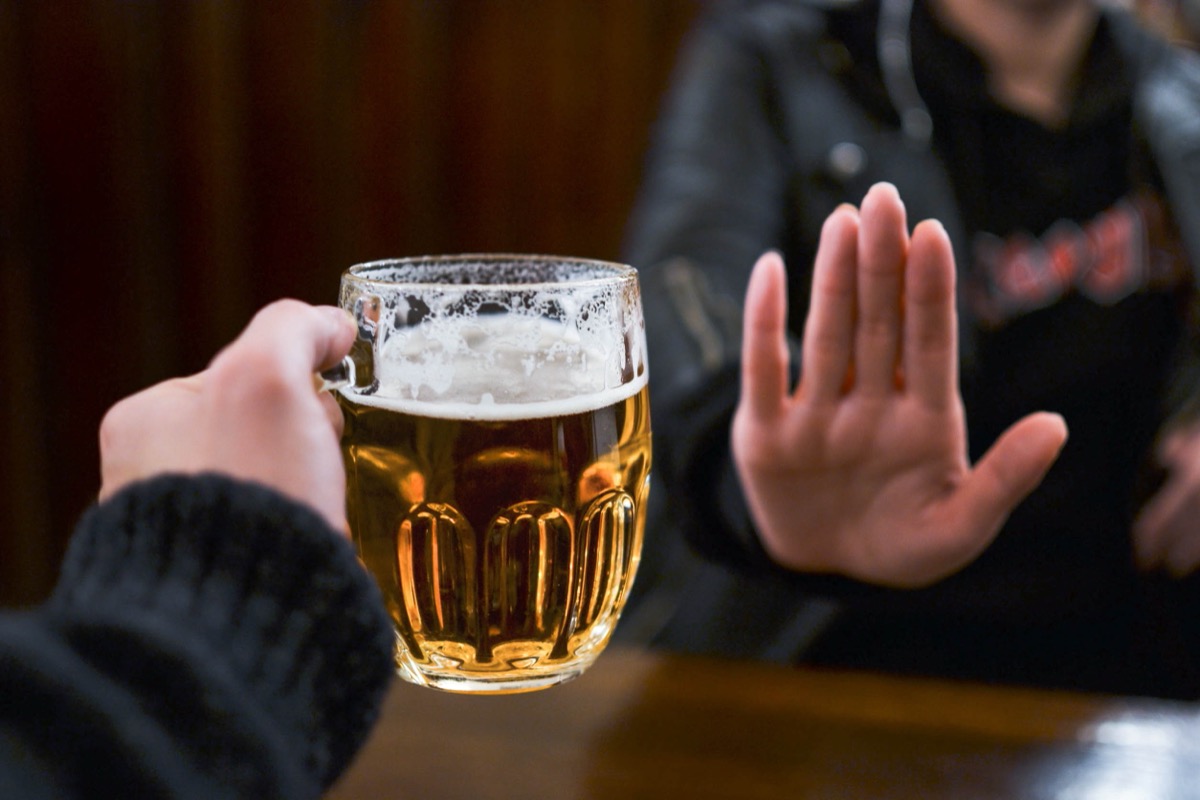person holding out hand to indicate they don't want a glass of beer