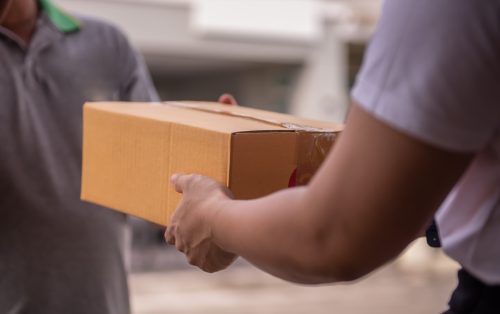 man handing cardboard box to person at postal office