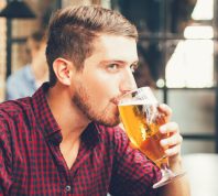 man drinking beer out of a glass