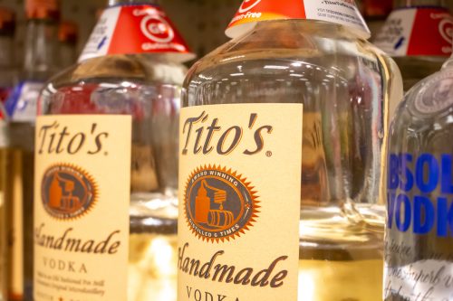 Two glass bottles of Tito's Handmade Vodka on a shelf at a grocery store