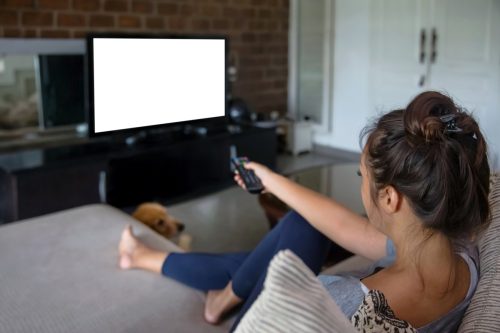 Shot of a young woman relaxing in front of her TV at the weekend
