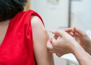 A closeup of a woman receiving a COVID vaccine from a healthcare worker