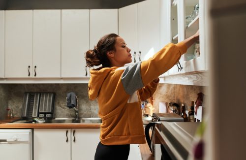 Một phụ nữ trẻ thò tay vào tủ bếp