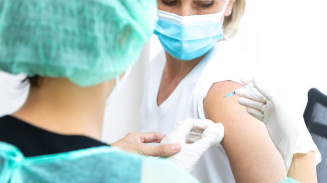 A middle-aged woman getting a COVID vaccine from a healthcare worker