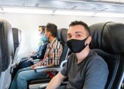 Airplane passengers are wearing medical masks on their faces. Air travel during the coronavirus pandemic. Airlines requirements