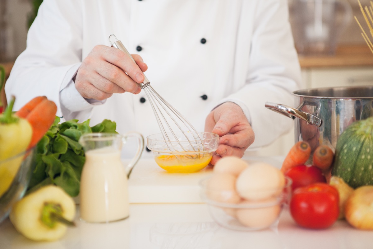 chef whisking a bowl of eggs in modern kitchen