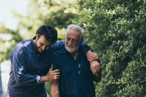 Alter Mann und sein Sohn, die in den Park gehen.  Ein Mann umarmt seinen alten Vater.  Sie sind glücklich und lächeln