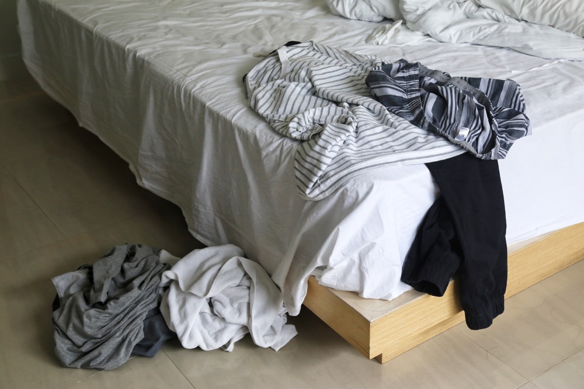 dirty clothes on bed and floor