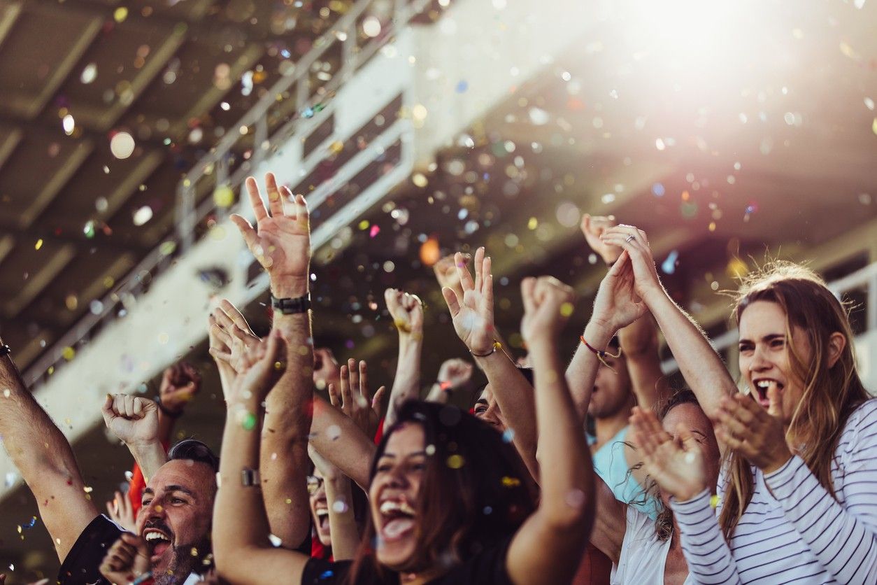 A crowd of fans cheering at a sporting event in an arena