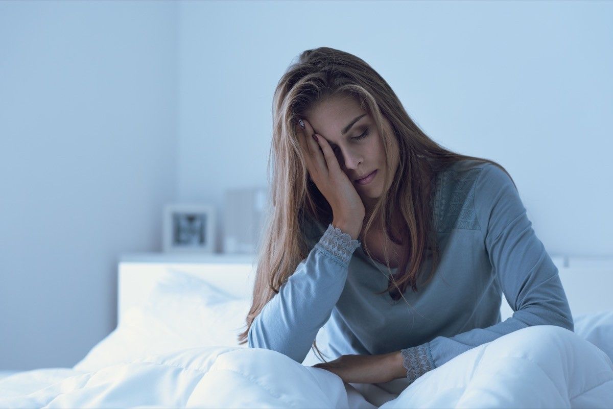 Depressed woman awake at night, she touches her forehead and suffers from insomnia