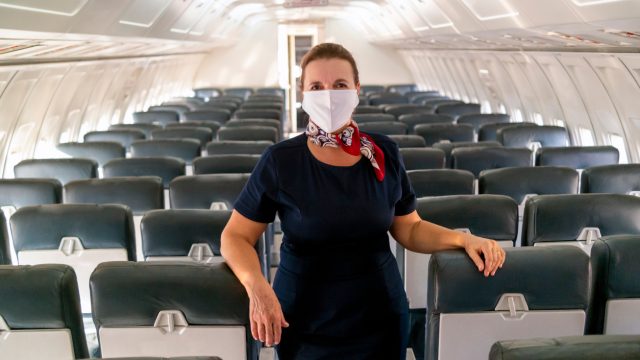 A flight attendant wearing a face mask onboard an empty plane