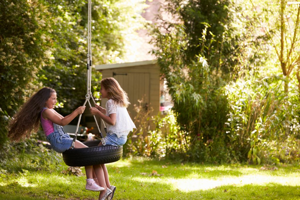 Two young girls playing on a tire swing