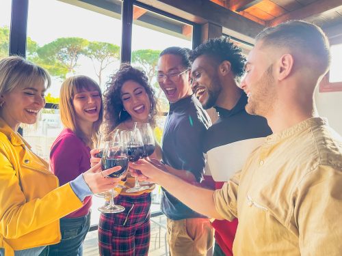 Grup de tineri scandând pahare de vin într-un bar
