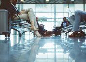 Low angle shot of travelers sitting in airport lounge area, waiting to board plane at the departure gates