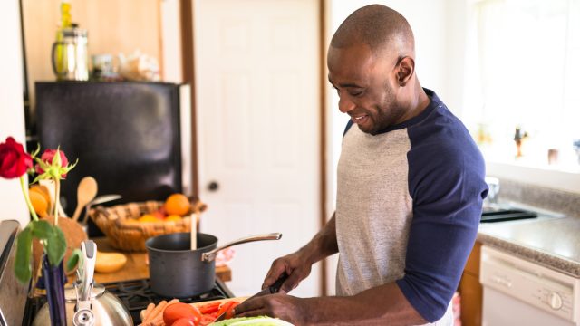 A man standing in his kitchen cooking food