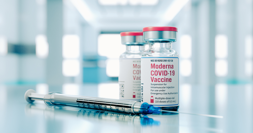Two vials of Moderna COVID-19 vaccine sitting next to a syringe