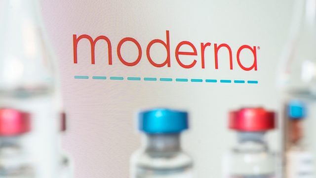 The Moderna company logo with vaccine vials in the foreground