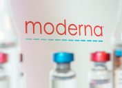 The Moderna company logo with vaccine vials in the foreground