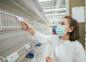 woman wearing mask and reading label on empty shelf in Supermarket in Bangkok, Thailand.