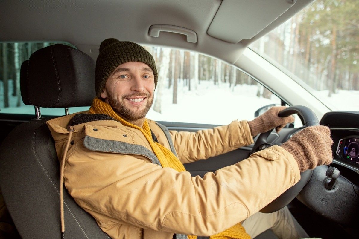 Man driving in a lot of layers and a scarf