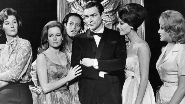 sean connery in black suit surrounded by women in james bond movie thunderball in a black and white still