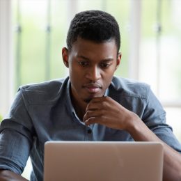 millennial male employee look at laptop screen working