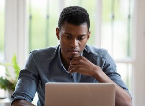 millennial male employee look at laptop screen working