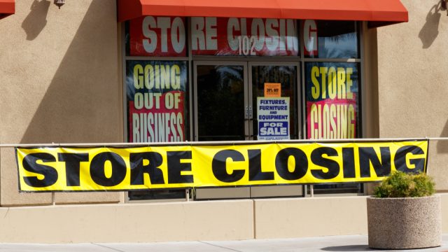 The front of a store going out of business with closing and liquidation signs