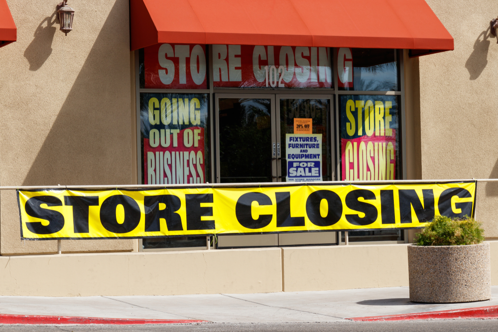 The front of a store going out of business with closing and liquidation signs