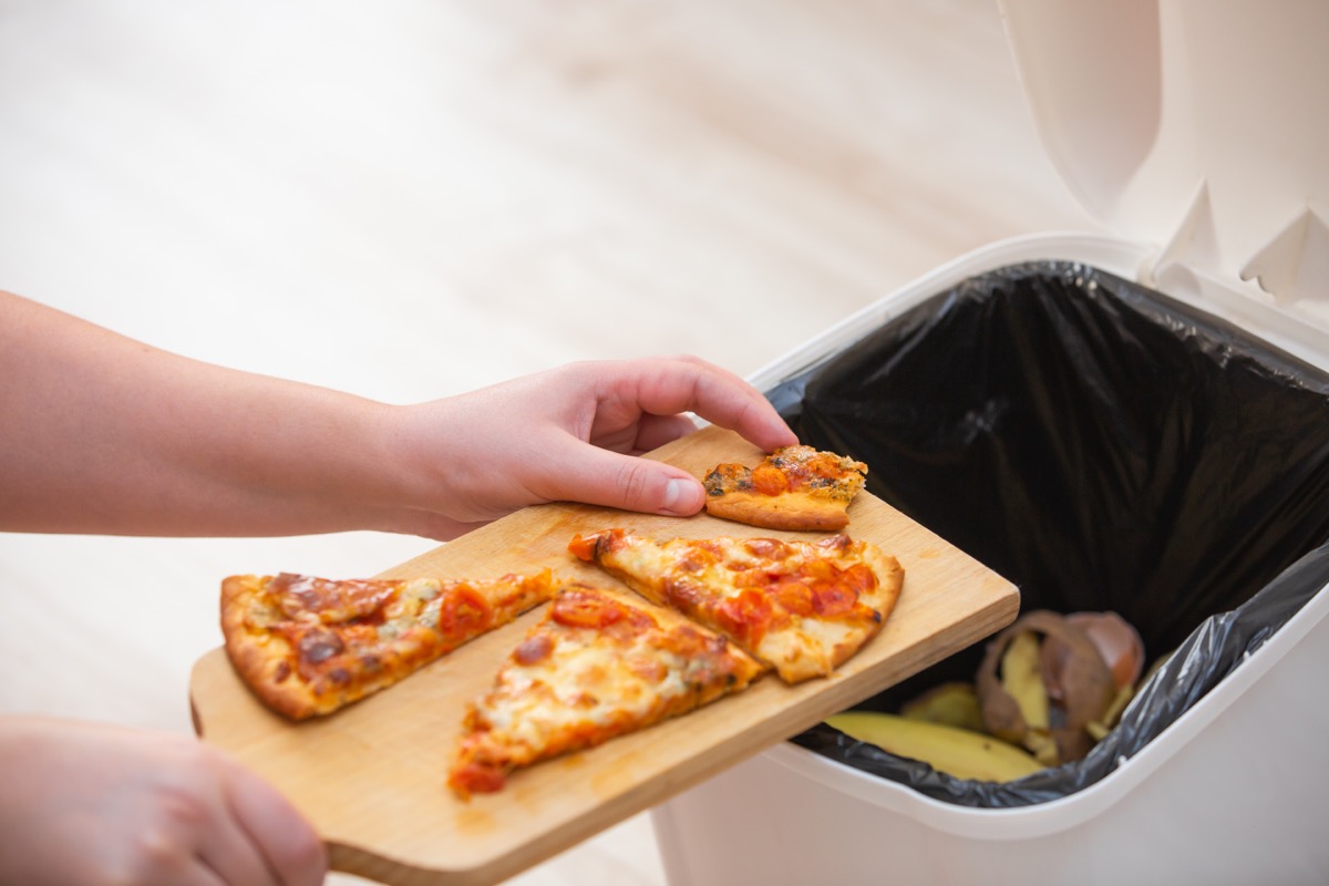 person throwing away pizza into trash can