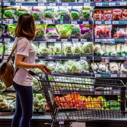 A woman is looking for organic vegetable in the shelf at supermarket.