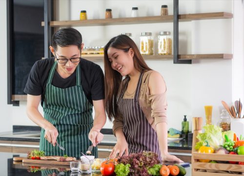 young couple cooking meat in kitchen