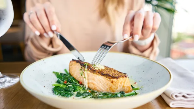 Hands of woman eating fish
