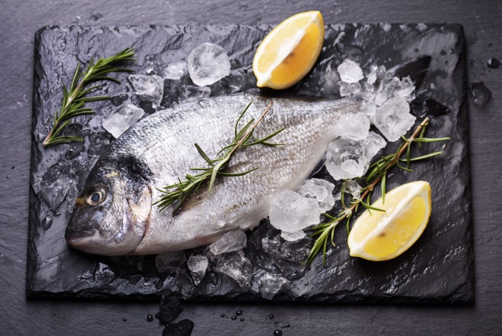 Fish with lemon and ice on cutting board