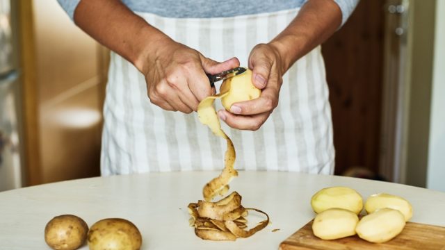 person in blue shirt peeling potatoes