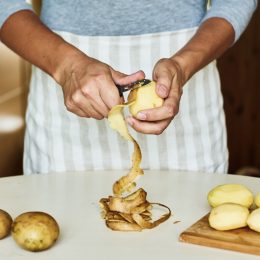 person in blue shirt peeling potatoes