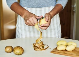 person in blue shirt peeling potatoes