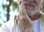 Close up of senior man holding jaw in discomfort or pain