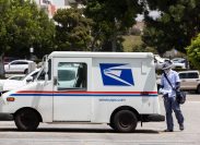 Fullerton, California / USA - August 13, 2020: A USPS (United States Parcel Service) mail truck and postal carrier make a delivery.