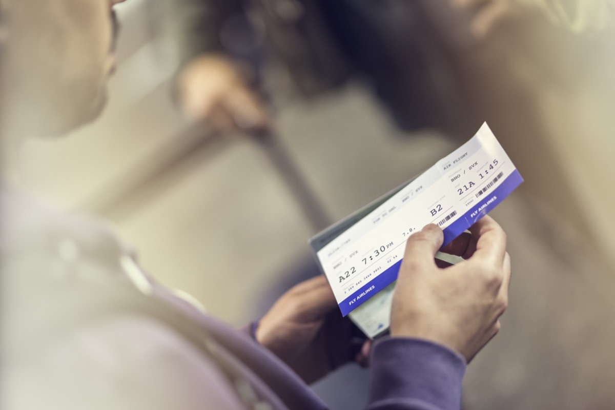 Close up of a man holing airplane ticket, blurred background.