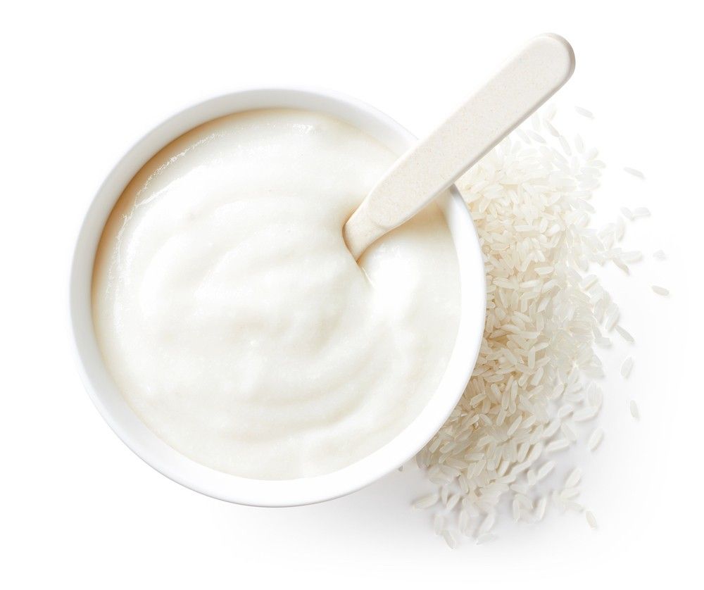 Bowl of baby rice cereal isolated on white background, top view