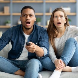 A couple watching TV who are angry or confused at the screen