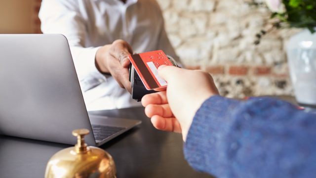 Guest makes card payment at check-in desk of hotel, detail
