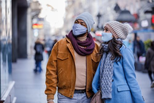 Couple with Face Masks Walking in the Street with Paper Bags After Shopping.